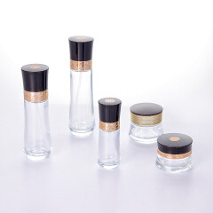 Wholesale luxury transparent glass bottle and jar with beautifully carved black cap for skincare packaging set